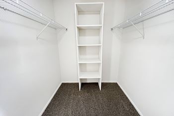 An empty closet in a room with white walls and shelves